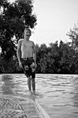BOY (AGED 13) JUMPING INTO A SWIMMING POOL. WALKING ON WATER. BLACK AND WHITE IMAGE