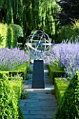 DAVID HARBER SUNDIALS: STONE PATH WITH ARMILLARY SPHERE SUNDIAL ON PLINTH IN FORMAL GARDEN SURROUNDED BY BOX HEDGES AND LAVENDER. EVENING LIGHT