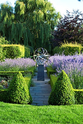DAVID_HARBER_SUNDIALS_STONE_PATH_WITH_STAINLESS_STEEL_ARMILLARY_SPHERE_SUNDIAL_IN_FORMAL_GARDEN_SURR