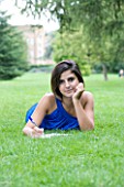 TEENAGE GIRL (16-17 YEARS) IN BLUE TOP LYING ON GRASS WRITING. SMILING  TEENAGE GIRLS  ONE TEENAGE GIRL ONLY  CASUAL CLOTHING  HAPPY  HAPPINESS  STUDENT  COLLEGE  IN THE PARK