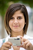 TEENAGE GIRL (16-17 YEARS) IN WHITE SHIRT TAKING A PHOTOGRAPH. BAG OVER SHOULDER. TEENAGE GIRLS  ONE TEENAGE GIRL ONLY  STUDENT  COLLEGE  CASUAL CLOTHING  PHOTOGRAPH  PHOTOGRAPHY