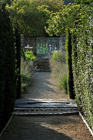 THROUGHAM_COURT__GLOUCESTERSHIRE_DESIGNER_CHRISTINE_FACER_VIEW_ALONG_YEW_HEDGES_TO_SLATE_STARBURST_B
