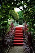 THROUGHAM COURT  GLOUCESTERSHIRE. DESIGNER: CHRISTINE FACER: THE ROYAL STEPS - RED CARPET UP STEPS WITH PHORMIUMS AND PLEACHED LIME WALK BEYOND