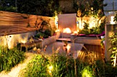 DESIGNER CHARLOTTE ROWE  LONDON: CHARLOTTE ROWES OWN GARDEN AT NIGHT - PORTUGUESE HONED LIMESTONE FLOORING  RENDERED RAISED BEDS AND FIREPLACE  PHILIPPE STARCK CHAIRS  TRELLIS