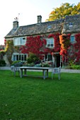 THE GRAY HOUSE  OXFORDSHIRE  DESIGNED BY TIM REES: BACK OF THE GRAY HOUSE IN AUTUMN WITH BOSTON IVY -  WOODEN TABLE AND BENCH ON THE LAWN