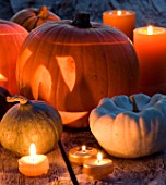 HALLOWEEN: STILL LIFE ON WOODEN TABLE AT NIGHT WITH CANDLES  PUMPKINS  GOURDS AND SQUASHES