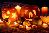 HALLOWEEN: STILL LIFE ON WOODEN TABLE AT NIGHT WITH CANDLES  PUMPKINS  GOURDS AND SQUASHES