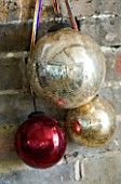 BOONSHILL FARM AT CHRISTMAS: THE LIVING ROOM - DECORATIVE CHRISTMAS BAUBLES ON THE FIREPLACE. DESIGNER: LISETTE PLEASANCE