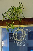 BOONSHILL FARM AT CHRISTMAS: THE DINING ROOM - MIRROR WITH MISTLETOE AND HANGING GLASS DECORATION. DESIGNER: LISETTE PLEASANCE