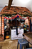 BOONSHILL FARM AT CHRISTMAS: THE KITCHEN WITH TABLE AND CHAIRS  AGA AND DECORATIONS. DESIGNER: LISETTE PLEASANCE