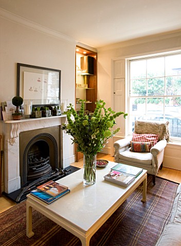 CHARLOTTE_ROWES_HOUSE__INTERIOR_SHOT_OF_LIVING_ROOM_WITH_TABLE_WITH_GREEN_FLORAL_DISPLAY_AND_VIEW_OU