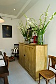 DESIGNERS SUE AYLETT: SUE AYLETTS HOUSE  LONDON: THE DINING ROOM - WOODN CABINET WITH GLASS JARS FILLED WITH WHITE GLADIOLI