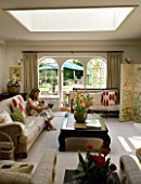 DESIGNERS SUE AYLETT: SUE AYLETTS HOUSE  LONDON: SUE AYLETT RELAXES IN HER LIVING ROOM WITH VIEW OUTSIDE TO THE GARDEN