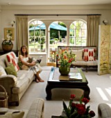 DESIGNERS SUE AYLETT: SUE AYLETTS HOUSE  LONDON: SUE AYLETT RELAXES IN HER LIVING ROOM WITH VIEW OUTSIDE TO THE GARDEN