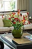 DESIGNERS SUE AYLETT: SUE AYLETTS HOUSE  LONDON: THE LIVING ROOM WITH BEAUTIFUL DISPLAY OF FLOWERS - CALLA LILIES  RANUNCULUS  TULIPS AND KANGAROO PAW IN GREEN CONTAINER