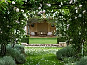 PRIVATE GARDEN  PROVENCE  FRANCE - DESIGNER DOMINIQUE LAFOURCADE. WOODEN PERGOLA WITH CLIMBING WHITE ROSE LEADING TO SEATING AREA