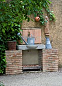 PRIVATE GARDEN  PROVENCE  FRANCE - DESIGNER DOMINIQUE LAFOURCADE. OUTDOOR BRICK AND STONE SINK WITH METAL WATERING CAN AND NESTING BOX