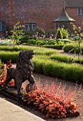 THE WALLED GARDEN AT COWDRAY  WEST SUSSEX. DESIGNER: JAN HOWARD - LION STATUE IN EARLY SUMMER BORDER WITH HEUCHERA MARMALADE AND LAVENDER HIDCOTE