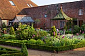 THE WALLED GARDEN AT COWDRAY  WEST SUSSEX. DESIGNER: JAN HOWARD - BOX EDGED BORDER WITH ALLIUM PURPLE SENSATION AND CHIVES WITH METAL GAZEBOS AND OLIVE TREE IN CONTAINER