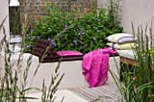 DESIGNER CHARLOTTE ROWE  LONDON: CHARLOTTE ROWES OWN GARDEN - RENDERED SEATING AREA WITH RAISED BED  CUSHIONS AND BRIGHT PINK THROW