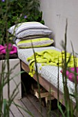 DESIGNER CHARLOTTE ROWE  LONDON: CHARLOTTE ROWES OWN GARDEN - WESTERN RED CEDAR SEAT WITH CUSHIONS AND LIME GREEN THROW
