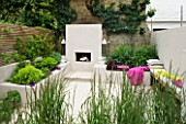 DESIGNER CHARLOTTE ROWE  LONDON: CHARLOTTE ROWES OWN GARDEN - PORTUGUESE HONED LIMESTONE FLOORING  RENDERED RAISED BEDS  FIREPLACE AND TRELLIS  SEATING AREA WITH CUSHIONS