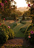 PETTIFERS  OXFORDSHIRE: DAWN LIGHT HITS THE PARTERRE FRAMED BY ROSE ARBOUR