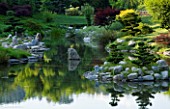 LA BAMBOUSERAIE DE PRAFRANCE  FRANCE: THE JAPANESE GARDEN - THE DRAGON VALLEY DESIGNED BY ERIK BORJA - THE LAKE WITH ROCKS AND CLOUD PRUNED CONIFERS. REFLECTION