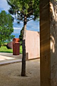 LA NORIA  FRANCE. GARDEN DESIGNED BY ARNAUD MAURIERES AND ERIC OSSART - A PINE TREE AND CONCRETE WALLS BESIDE THE GARDEN ENTRANCE