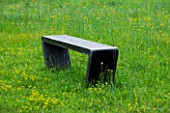 LA NORIA  FRANCE. GARDEN DESIGNED BY ARNAUD MAURIERES AND ERIC OSSART -  A BLACK CONCRETE BENCH IN THE PRAIRIE DE SCULPTURES - A PLACE TO SIT