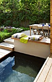 DESIGNER: CHARLOTTE ROWE  LONDON: FORMAL TOWN/CITY GARDEN WITH POOL AND DECK WITH TABLE AND CHAIRS  CUSHIONS AND THROW. RELAXED ENTERTAINING  DINING