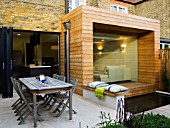 GARDEN DESIGNER: CHARLOTTE ROWE  LONDON: VIEW OF KITCHEN AND DINING AREA WITH GLASS AND TIMBER EXTENSION WITH POOL AND DECK