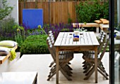 DESIGNER: CHARLOTTE ROWE  LONDON: OUTDOOR DINING AREA IN FORMAL TOWN/CITY GARDEN WITH TABLE AND CHAIRS AND BLUE FEATURE WALL. RELAXED ENTERTAINING.