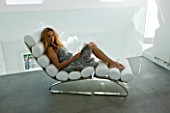 TANIA LAURIE  LONDON. TANIA RELAXES ON A CONTEMPORARY WHITE CHAIR IN BEDROOM