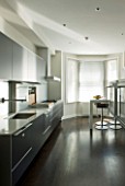TANIA LAURIE  LONDON. CONTEMPORARY KITCHEN WITH BLACK UNITS  WOODEN FLOOR AND BREAKFAST BAR