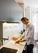 TANIA LAURIE  LONDON. TANIAS PARTNER DANIEL PREPARES LUNCH IN THEIR STYLISH  CONTEMPORARY KITCHEN
