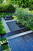 TANIA LAURIE  LONDON. OVERVIEW OF SMALL CONTEMPORARY GARDEN BY CHARLOTTE ROWE. BLACK PAINTED DECK WITH GREY PEBBLED PATIO WITH BLACK MARBLE TABLE AND CATALPA ON THE RIGHT