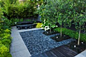 TANIA LAURIE  LONDON. SMALL CONTEMPORARY GARDEN BY CHARLOTTE ROWE. EATING/ENTERTAINING AREA WITH POLISHED GREY PEBBLES WITH OPHIOPOGON PLANTED INTO SQUARES WITH CATALPA