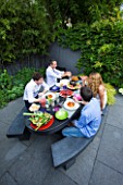 TANIA LAURIE  LONDON. TANIA AND FAMILY SIT DOWN TO LUNCH IN THEIR CONTEMPORARY GARDEN DESIGNED BY CHARLOTTE ROWE