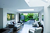 TANIA LAURIE  LONDON. INTERIOR OF LIVIN AREA LEADING OUT ONTO PATIO AND CONTEMPORARY GARDEN DESIGNED BY CHARLOTTE ROWE