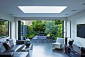 TANIA LAURIE  LONDON. INTERIOR OF LIVING AREA LEADING OUT ONTO PATIO AND CONTEMPORARY GARDEN DESIGNED BY CHARLOTTE ROWE