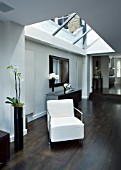 TANIA LAURIE  LONDON. INTERIOR OF LIVING AREA WITH GLASS ROOF (ROOFLIGHT) AND WHITE CHAIR WITH WOODEN FLOOR