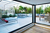 CONTEMPORARY FORMAL ROOF TERRACE/ GARDEN DESIGNED BY DATA NATURE ASSOCIATES: VIEW OUT OF APARTMENT TO SEATING AREA  BARBEQUE  SUN LOUNGERS AND CUSHIONS