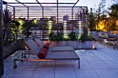 CONTEMPORARY FORMAL ROOF TERRACE/ GARDEN DESIGNED BY DATA NATURE ASSOCIATES: VIEW OUT OF APARTMENT TO SEATING AREA  WITH SUN LOUNGERS AND CUSHIONS  TRELLIS AND LIGHTING AT NIGHT