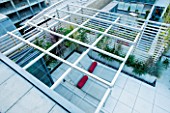 CONTEMPORARY FORMAL ROOF TERRACE/ GARDEN DESIGNED BY DATA NATURE ASSOCIATES: VIEW DOWN OVER TRELLIS PERGOLA TO SEATING AREA WITH SUN LOUNGERS AND CUSHIONS