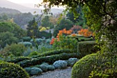 PROVENCE  FRANCE: GARDEN OF NICOLE DE VESIAN  LA LOUVE: CLIPPED TOPIARY AND RHUS TYPHINA (STAGS HORN SUMACH)  AND COUNTRYSIDE (GARRIGUE) BEYOND