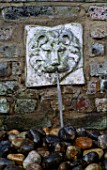 WATER FEATURE: WALL MOUNTED LIONS HEAD WATER SPOUT ABOVE STONE SINK FILLED WITH PEBBLES.  DESIGNER: ANTHONY NOEL