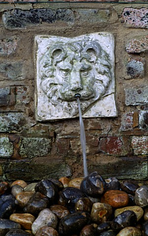 WATER_FEATURE_WALL_MOUNTED_LIONS_HEAD_WATER_SPOUT_ABOVE_STONE_SINK_FILLED_WITH_PEBBLES__DESIGNER_ANT