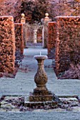 WOLLERTON OLD HALL  SHROPSHIRE: WINTER GARDEN IN FROST - VIEW FROM SUMMERHOUSE THROUGH BEECH HEDGING AT DAWN WITH SUNDIAL AND GATE IN DISTANCE. LAWN WITH FROST