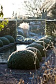 WOLLERTON OLD HALL  SHROPSHIRE: WINTER GARDEN IN FROST -  THE RILL GARDEN WITH CANAL LINED WITH BOX BALLS. DAWN LIGHT